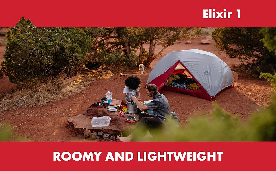 A couple camping and eating on a natural rock table with a dog in the background and the fully set up MSR Elixir 1 tent.