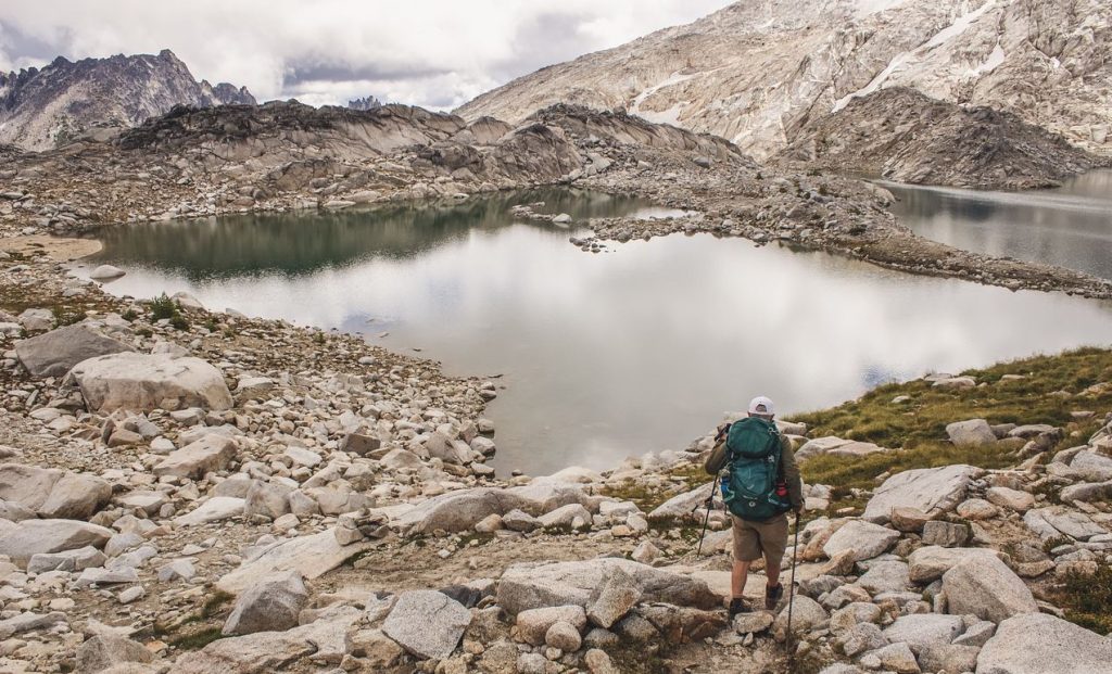 A backpacker standing in the tundra looking at a mountain lake, but is the water OK to drink?