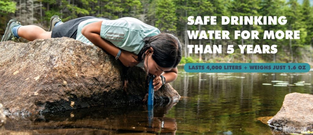 Woman using the LifeStraw Personal Water Filter in a river to purify her drinking water.