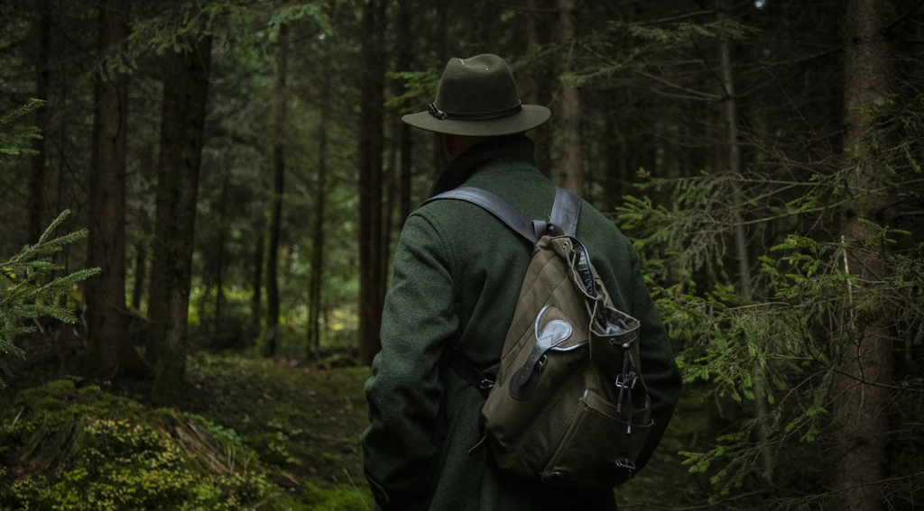 A man walking a trail alone as it gets dark, but staying calm with hands in pockets as he gets his bearings.