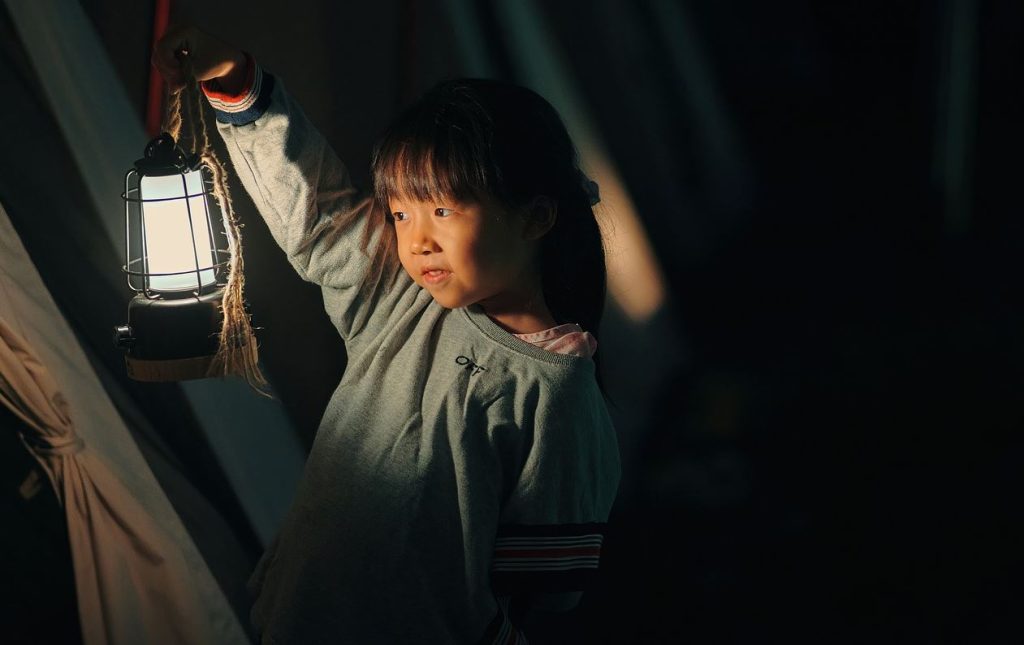 Young girl holding a lantern getting ready to hear a good campfire story. It's important to know your audience.