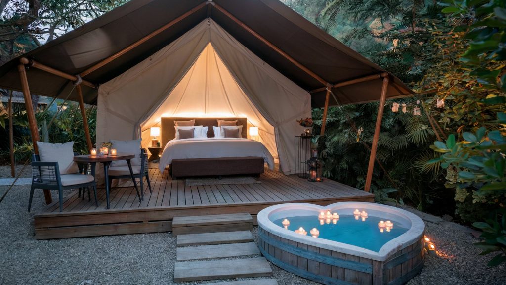 A glamping spa retreat for couples, showing a heart shaped tub and a luxury glamping tent in a jungle setting.