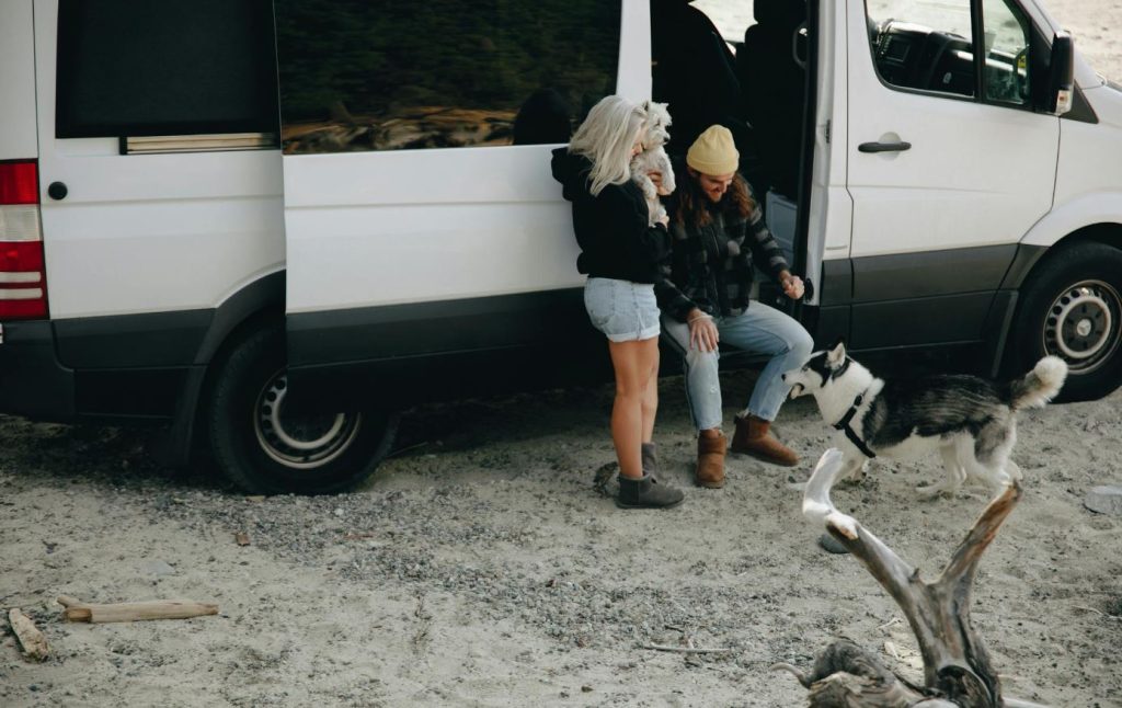 A young couple with their two dogs getting ready to travel in their RV with pets.