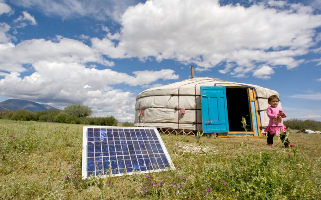 A solar panel on the ground outside a traditional yurt tent in Mongolia.