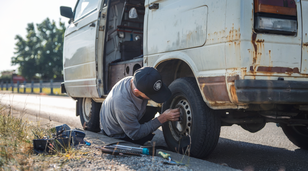 A man working on his van's tires. DIY van maintenance is essential when trying to keep a budget on the road.