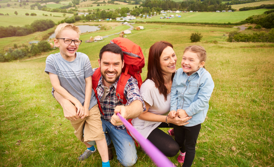 A mother and father with their son and daughter out for a hike with a glampground in the distance. Glamping provides easy entertainment for kids.