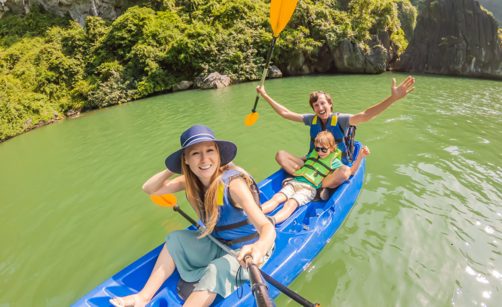 A smiling husband, wife and their son are kayaking in a relaxed, tropical environment. 