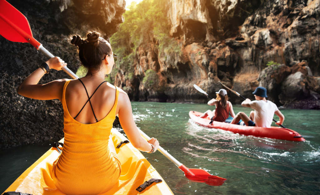 Three friends kayaking in a cave river showing off beginner kayaks, one yellow, one red.