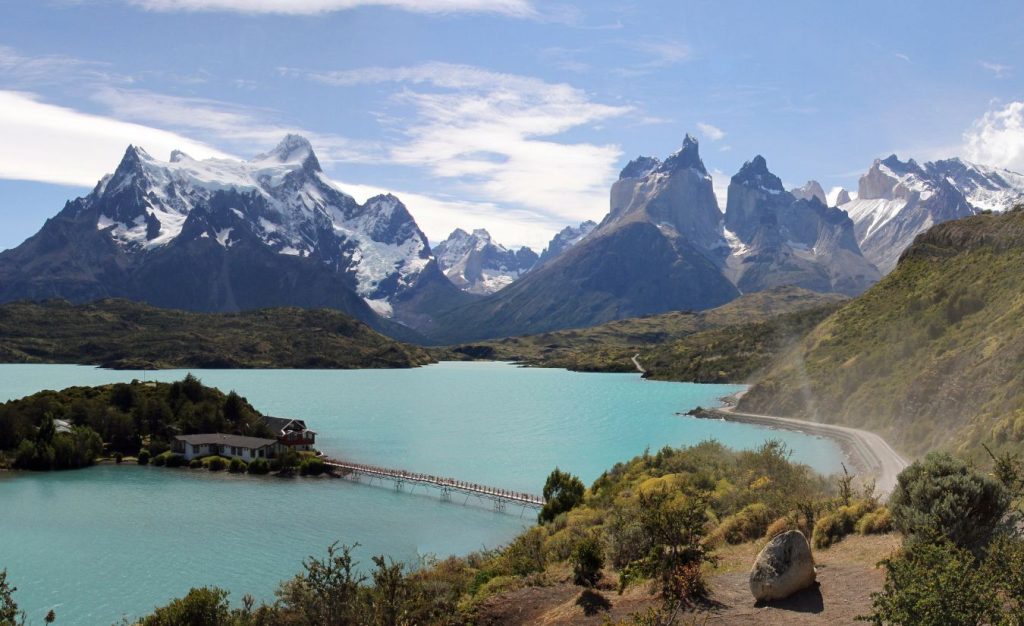 Torres del Paine Park in Chile. W trek on a sunny day with the bridge, coastal road and massive snowy peaks in the distance.