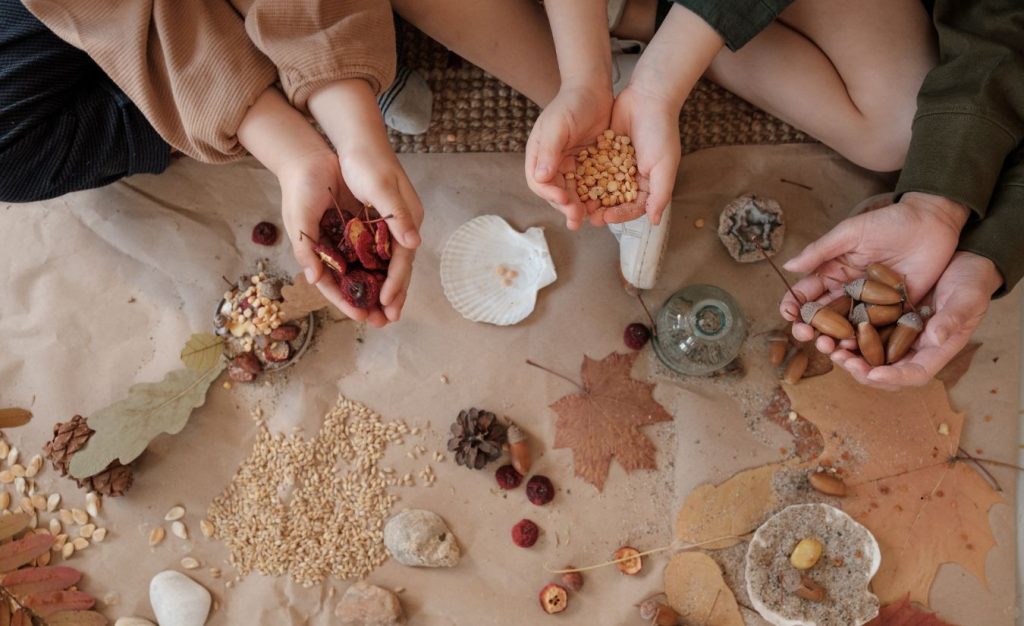 A group sitting on the ground holding some of their foraging bounty and learning more about foraging skills. 