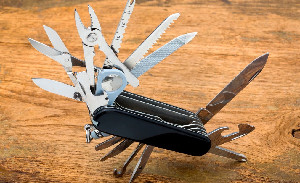 A camping multitool shown open on a wooden surface. 