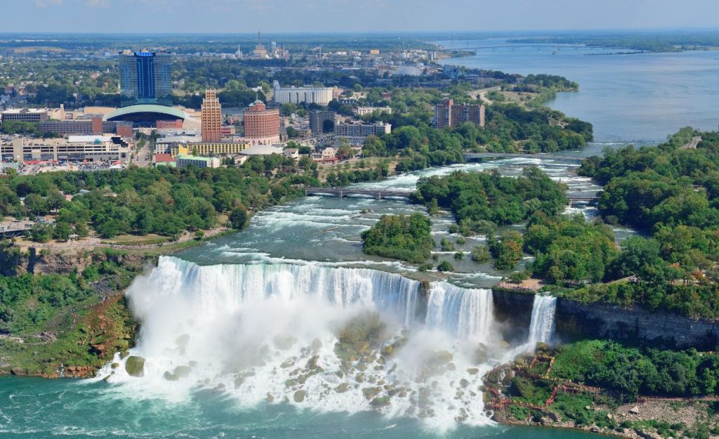 Niagara Falls seen from above with resorts and cityscape in the background.